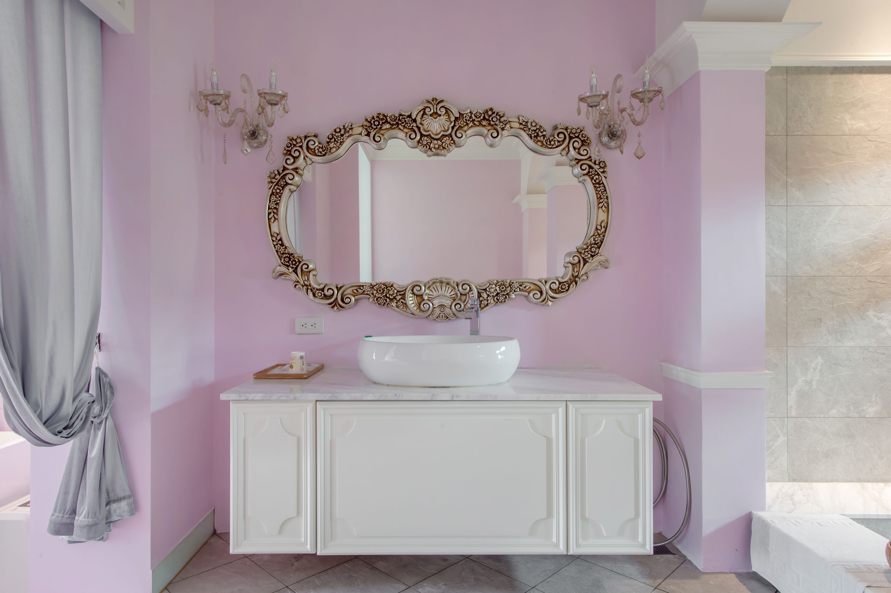 A bathroom with a white vanity, a large ornate mirror, and a white sink.