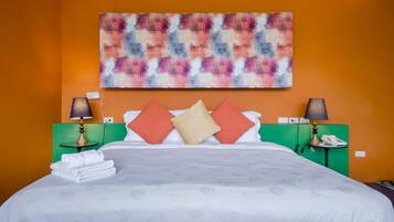 A hotel room with a bed, two nightstands, a lamp, a phone, and a colorful abstract painting on the wall.