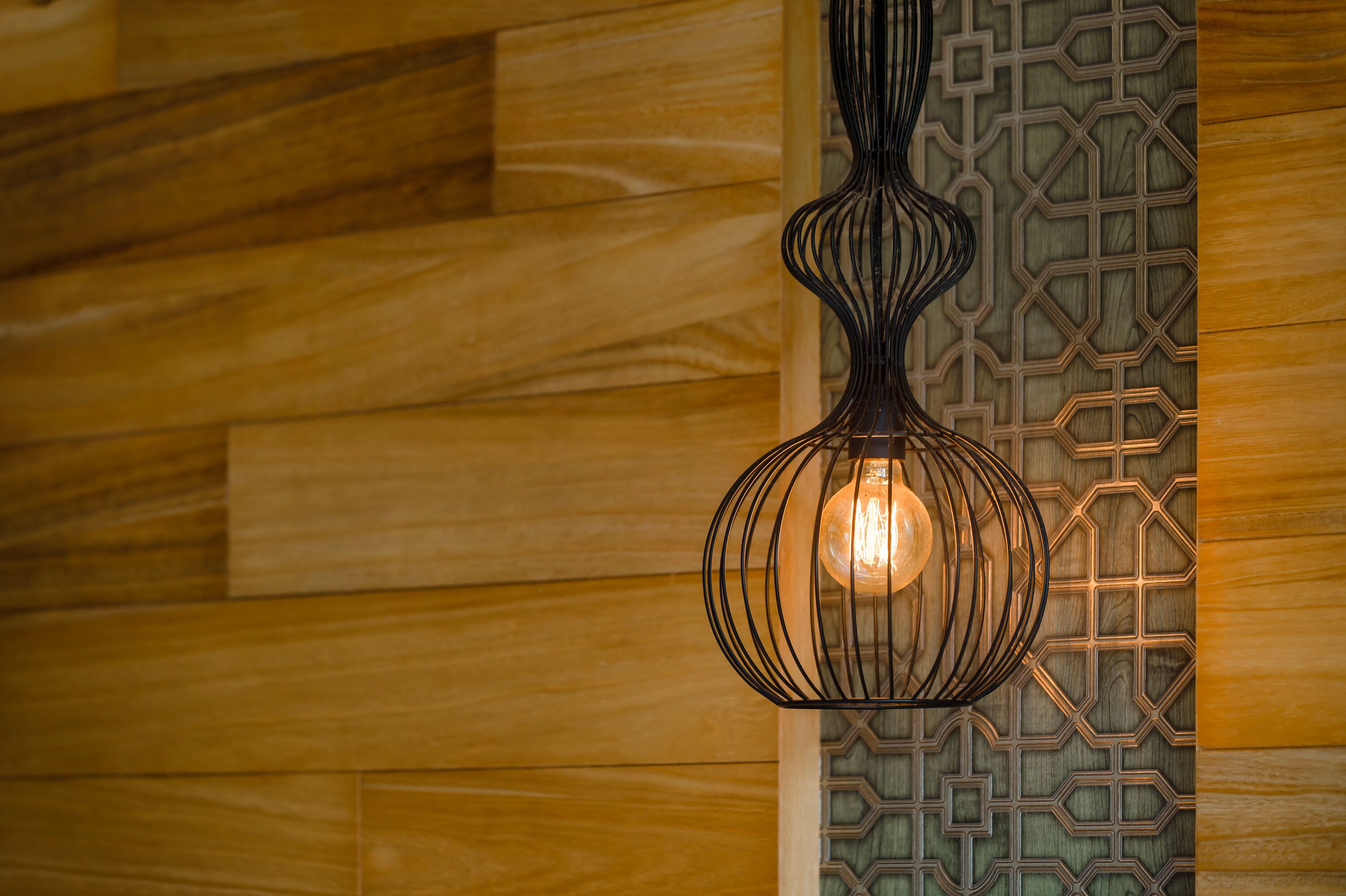 A hanging light fixture with a geometric pattern on the wall behind it.