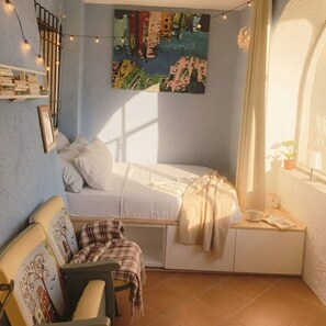 A cozy bedroom with a bed, a chair, a small table, and a window with curtains. - LA SBILENCHINA (Calice Ligure)