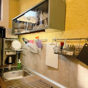 A kitchen with a sink, a dish rack, a utensil holder, and a spice rack. - LA SBILENCHINA (Calice Ligure)