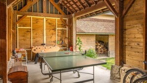 A ping pong table in a rustic wooden room with exposed beams and a fireplace. - Charming cottage with enclosed garden in Green Picardy (Martincourt)