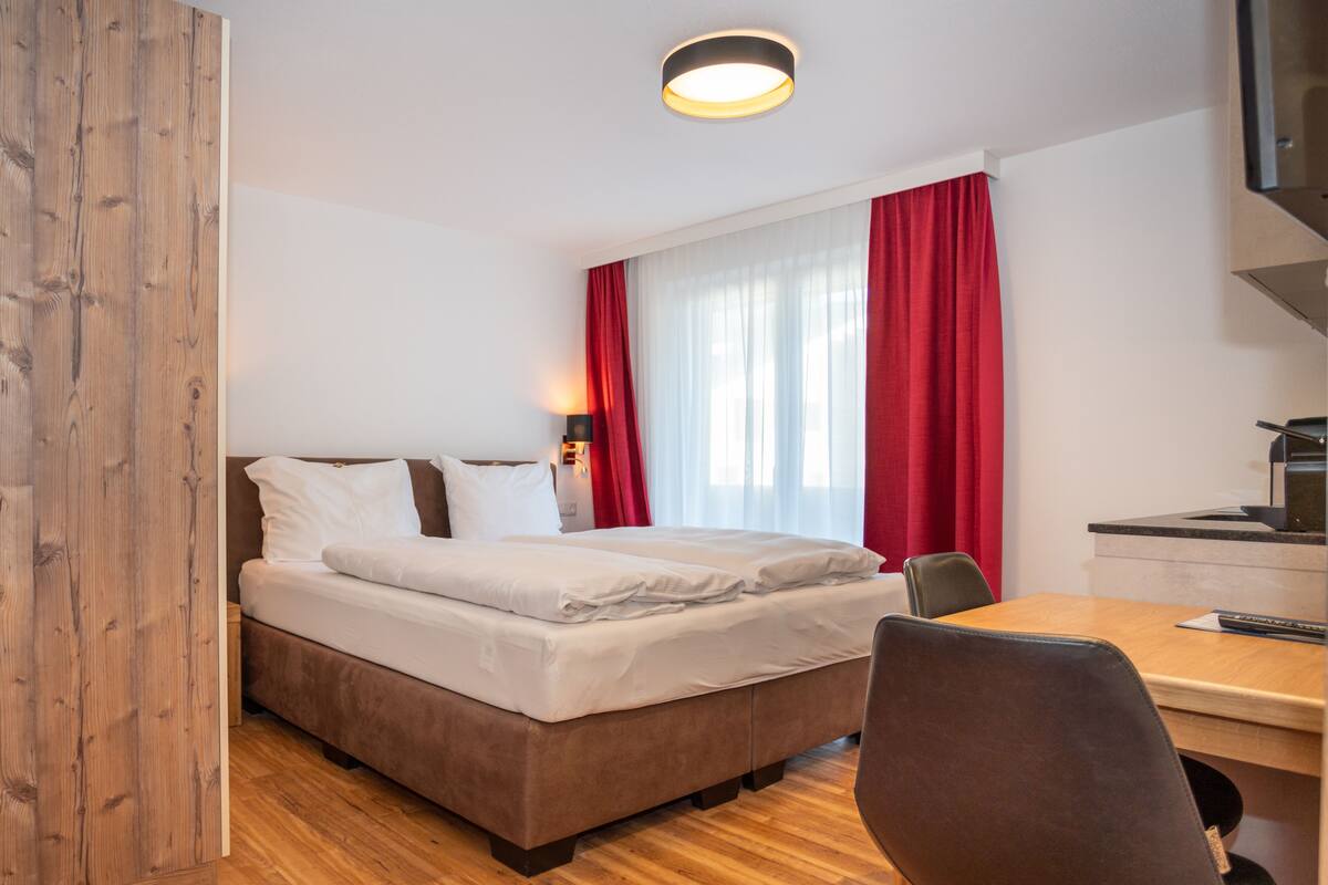 A hotel room with a bed, a desk, and a chair.