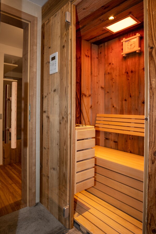 A wooden sauna room with a bench and a control panel.