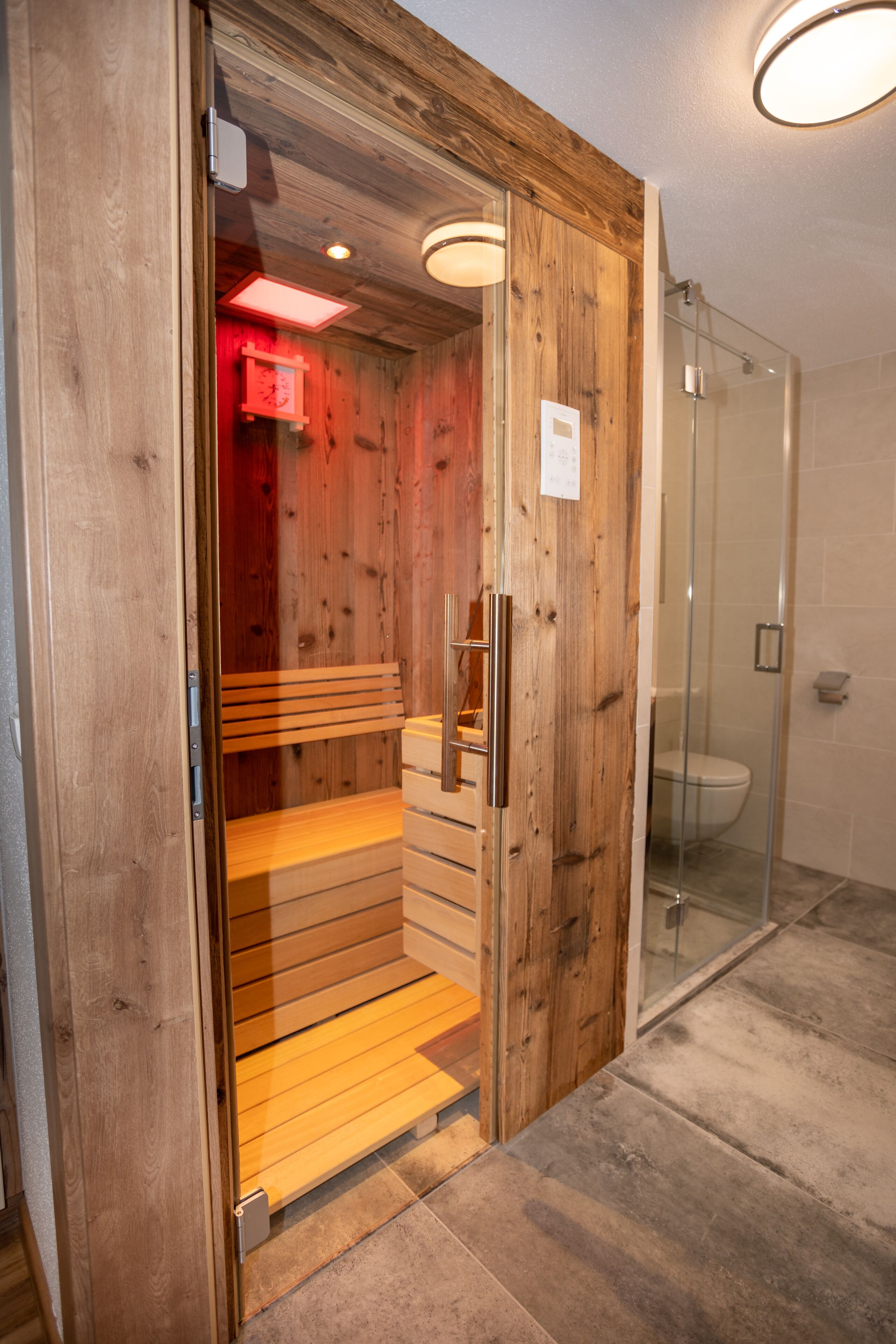 A wooden interior with a bench, a glass shower enclosure, and a toilet.