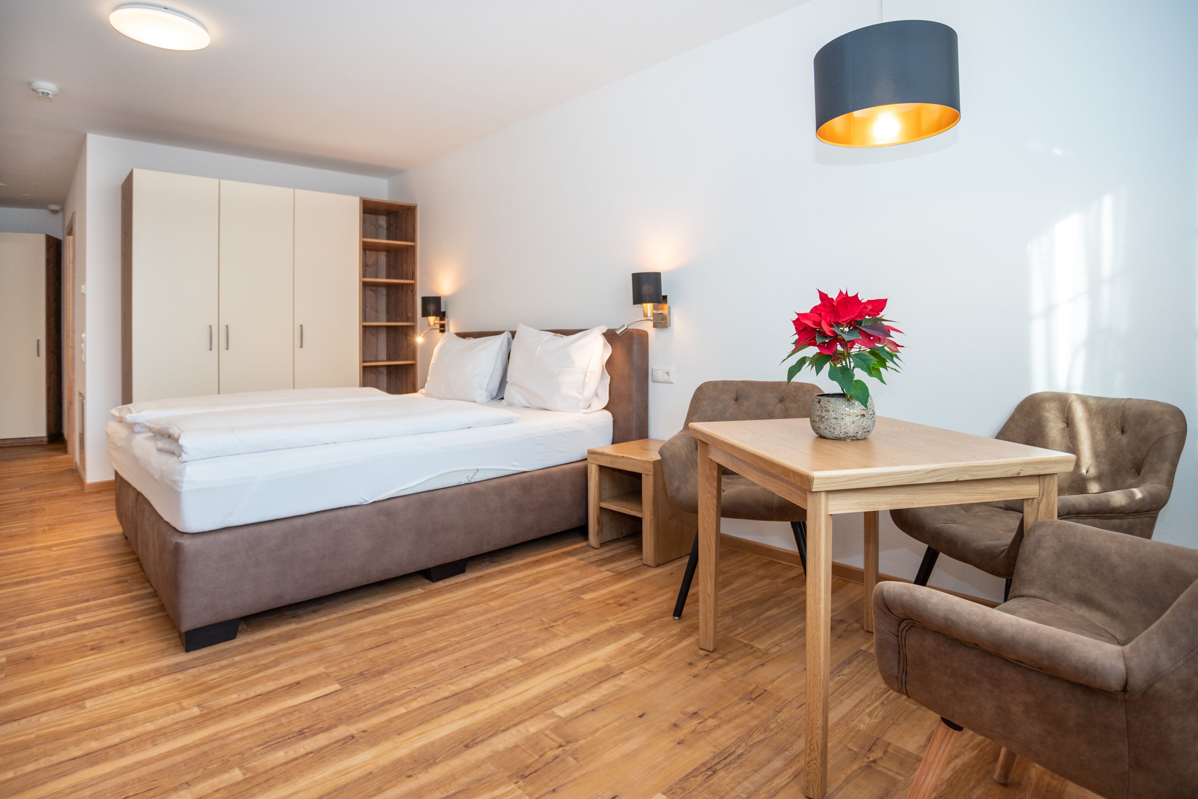 Un dormitorio moderno con cama, escritorio, silla y planta en maceta.