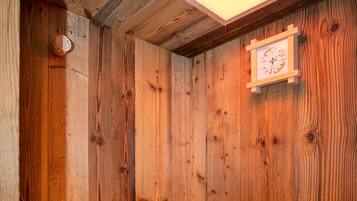 A wooden sauna with a bench, a small heater, and a clock on the wall.