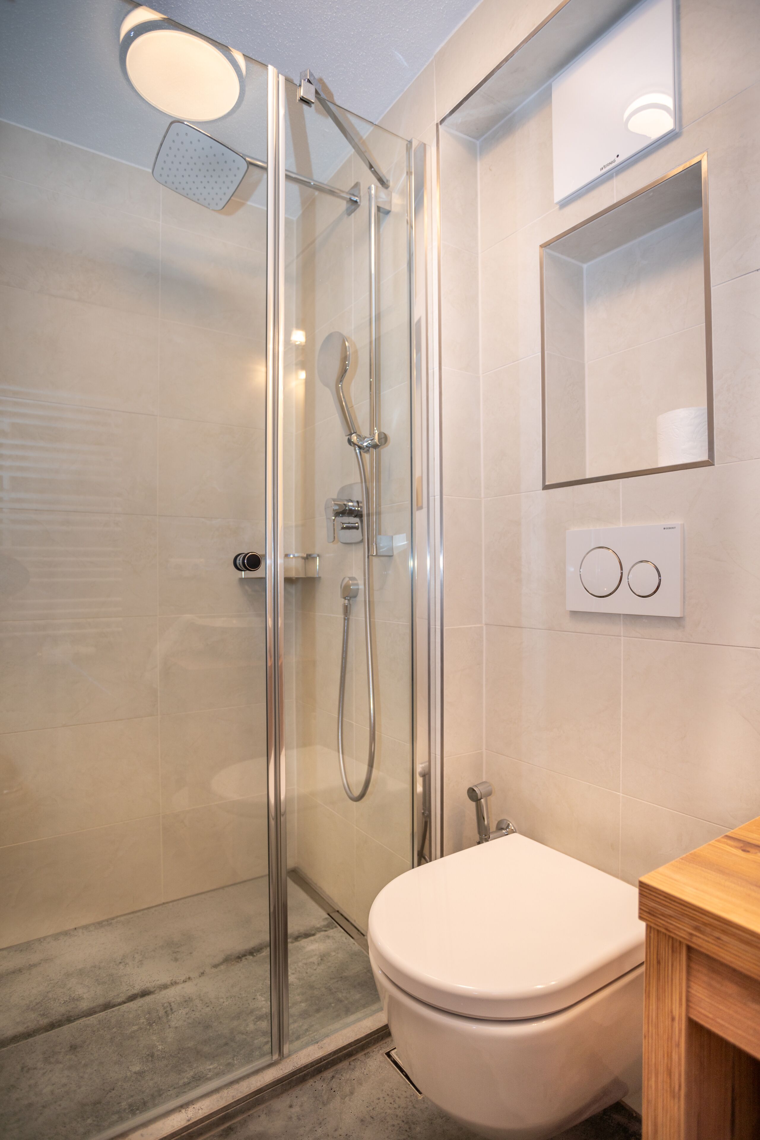 Une salle de bain moderne avec une douche à parois de verre, des toilettes et un meuble-lavabo en bois.