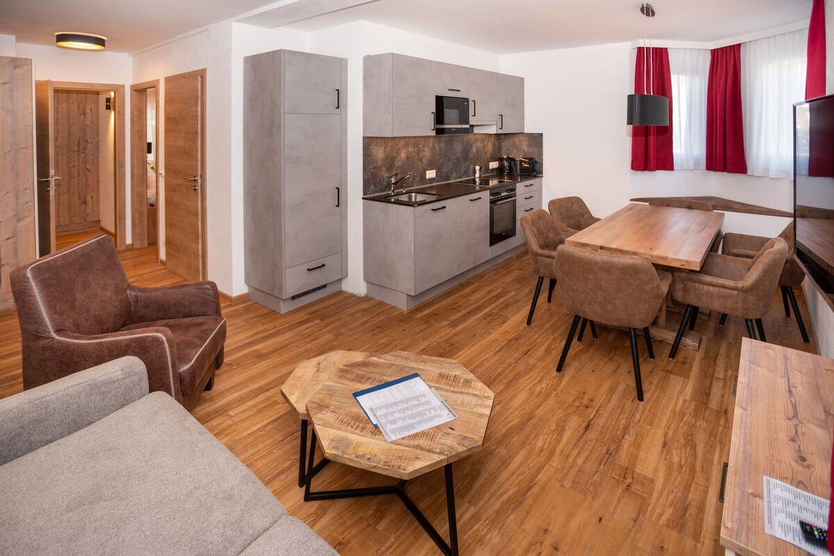 A modern kitchen with grey cabinets, a microwave, and a stove. There is a dining area with a wooden table and chairs.
