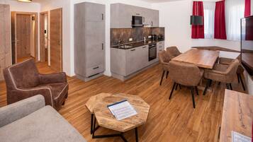 Una cocina moderna con armarios grises, un microondas y una estufa. Hay un comedor con una mesa y sillas de madera.