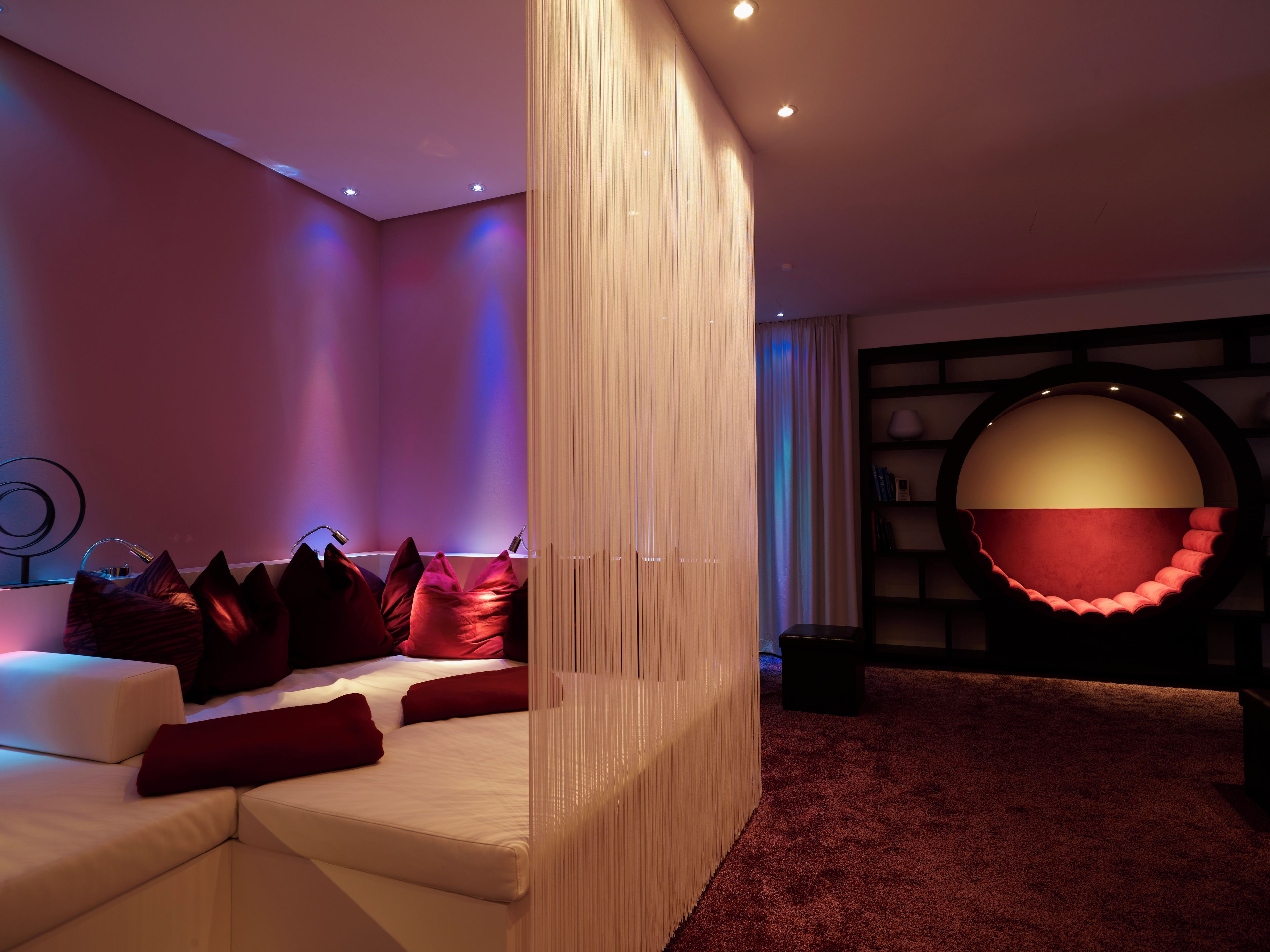 Ein modernes Schlafzimmer mit einer Eckcouch, einer runden Sitzecke und einem Bücherregal.