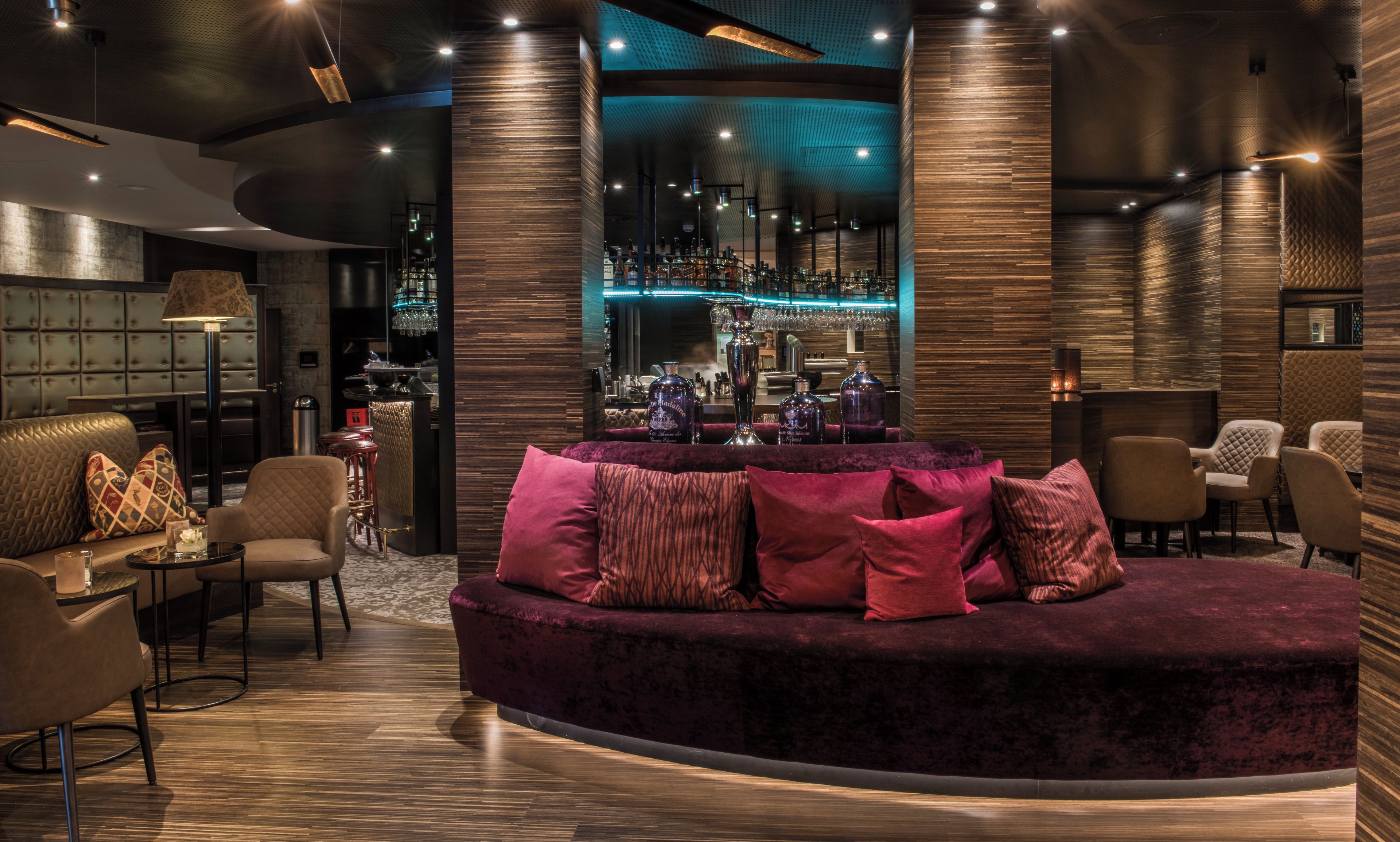 A modern lounge area with a curved sofa, bar, and seating.