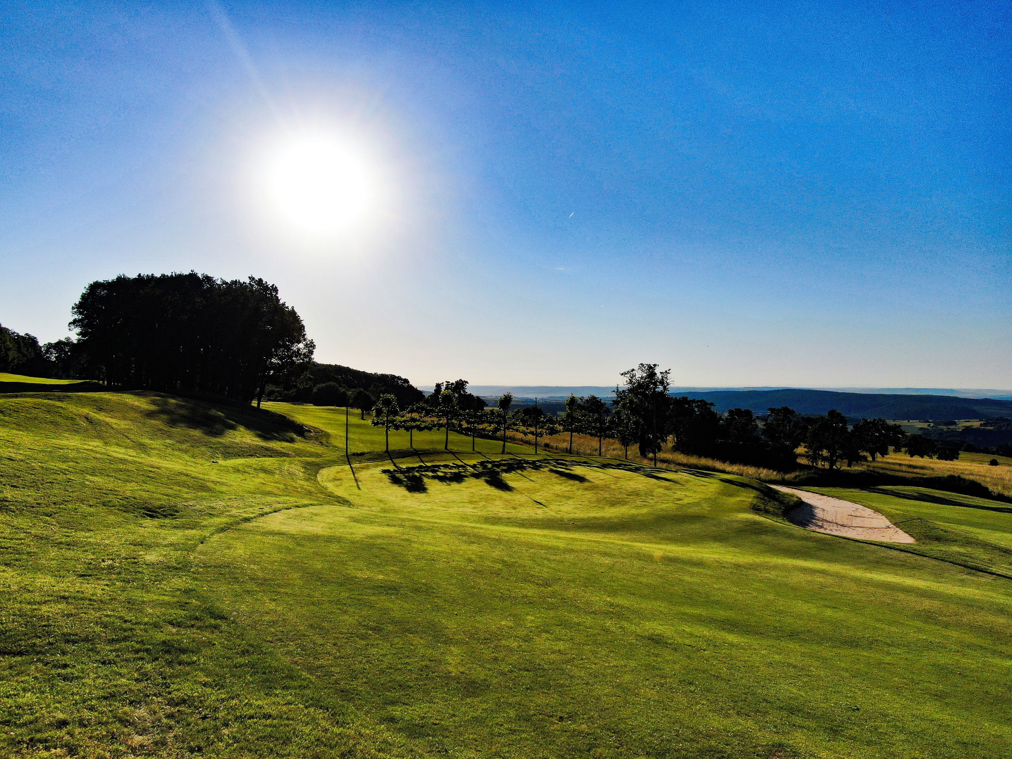 A golf course with a clear sky and distant hills.