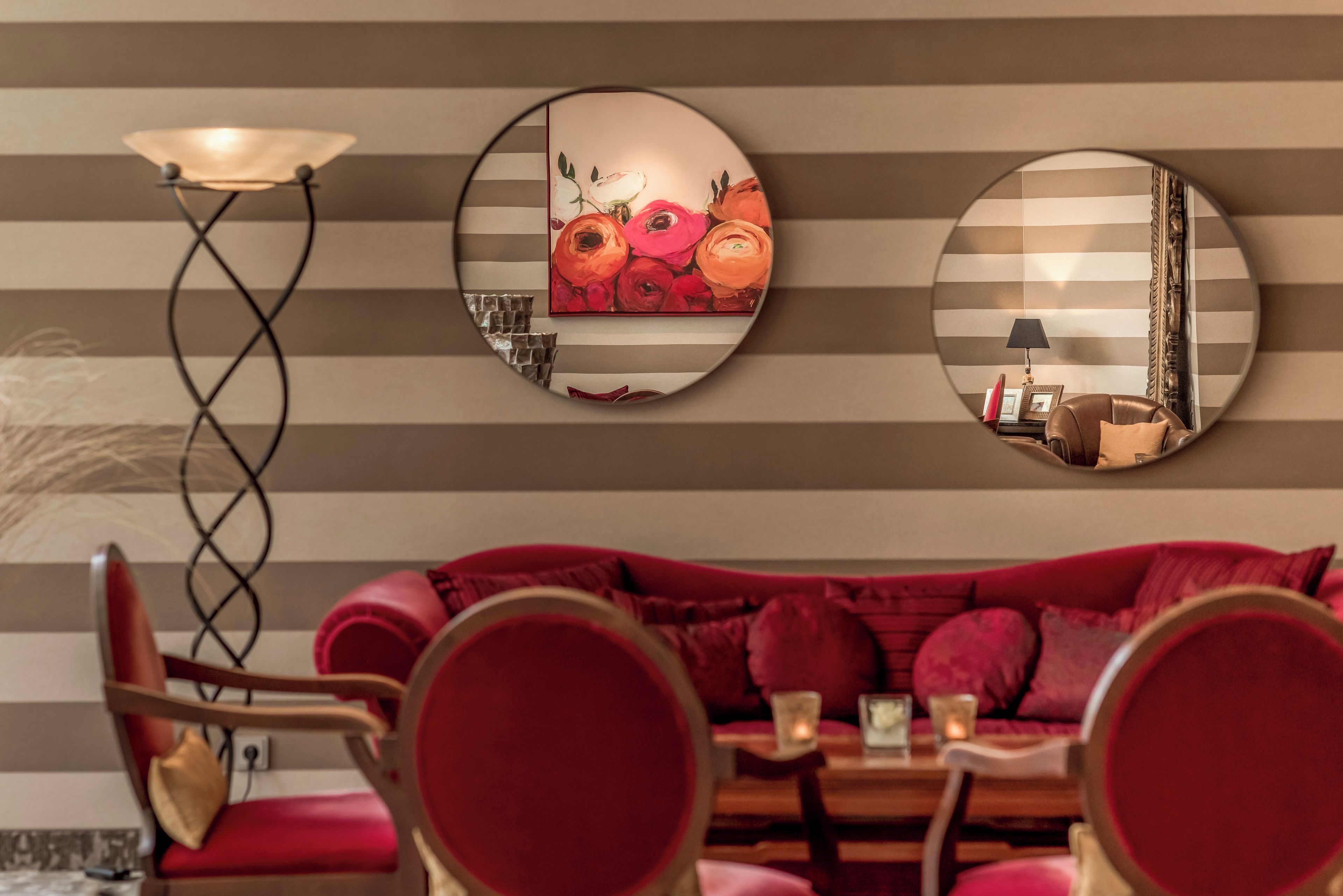 A room with a striped wall, a sofa, a table, and a lamp.