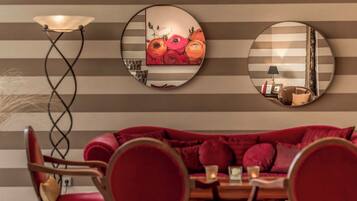 A room with a striped wall, a sofa, a table, and a lamp.