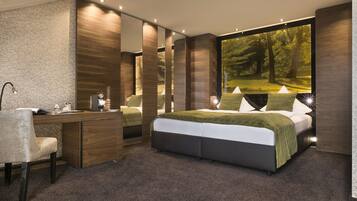 A modern bedroom with a large bed, a desk, and a large window with a forest view.