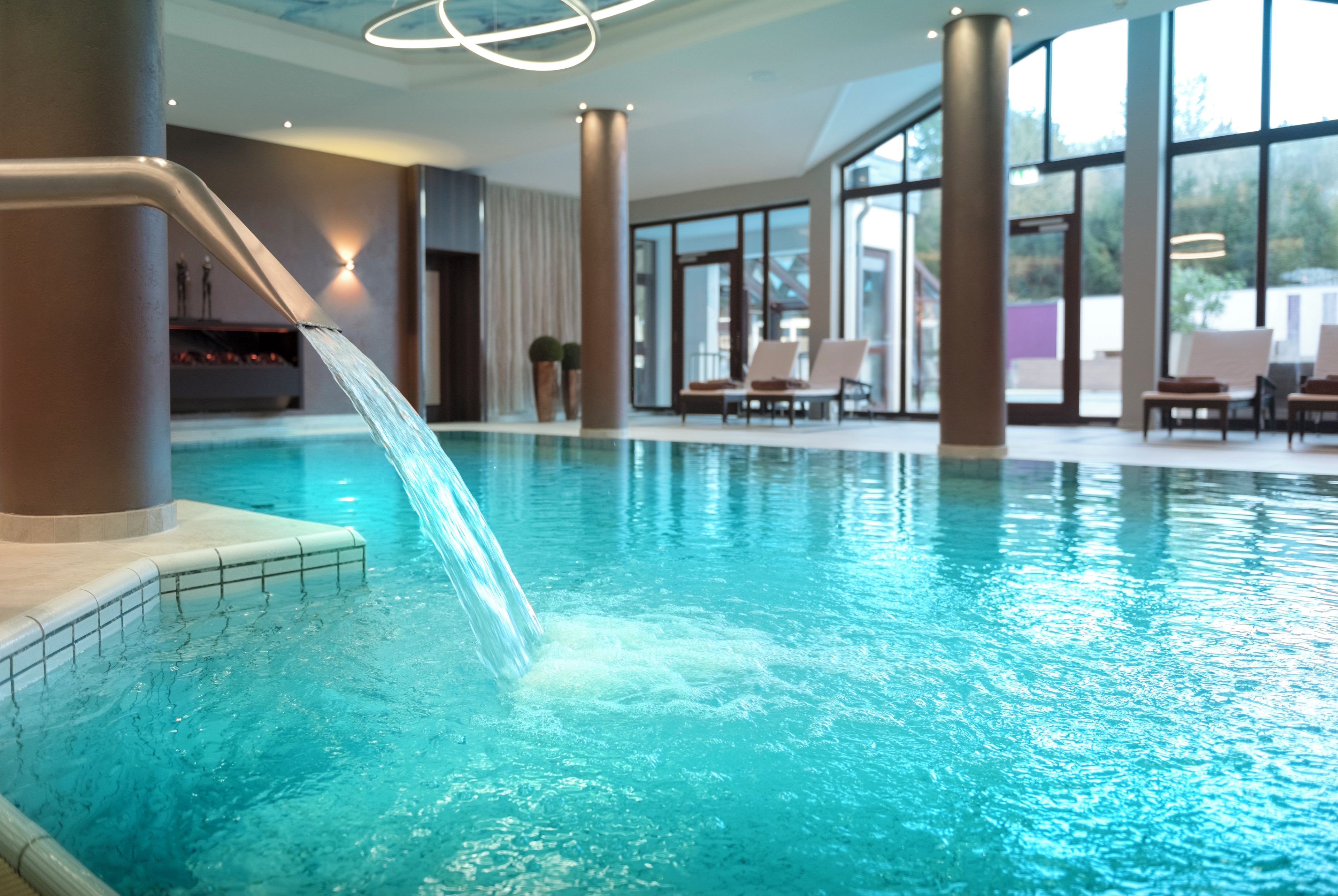 Ein Hallenbad mit Wasserrutsche, großen Fenstern und modernem Design.