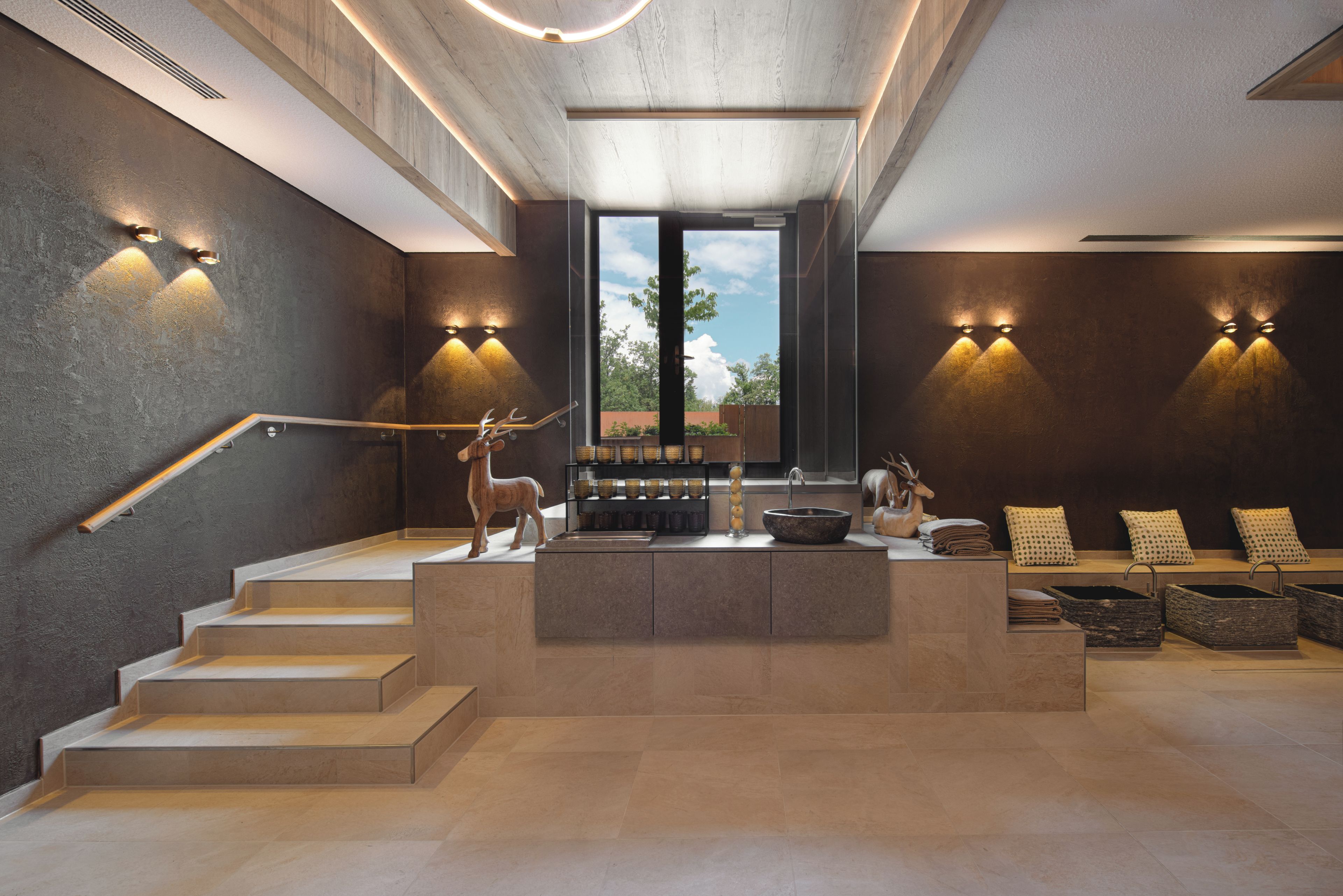 A modern interior with a central island, steps leading up to it, and wall-mounted lighting.
