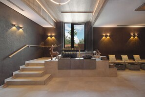 A modern interior with a central island, steps leading up to it, and wall-mounted lighting. - Land  & Golf Hotel Stromberg (Stromberg)