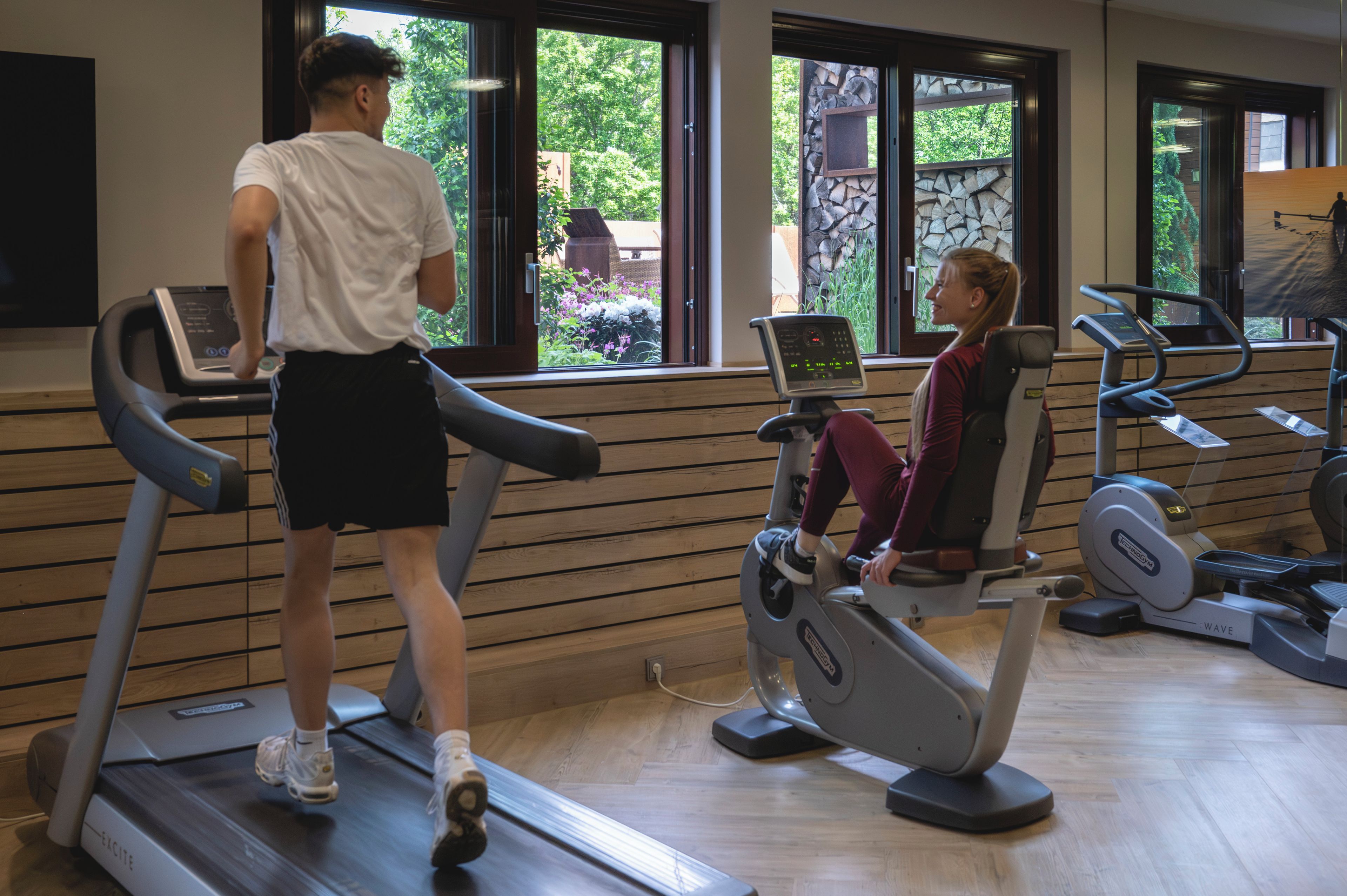 A gym with treadmills, stationary bikes, and a person using a treadmill.