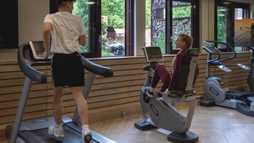 A gym with treadmills, stationary bikes, and a person using a treadmill.