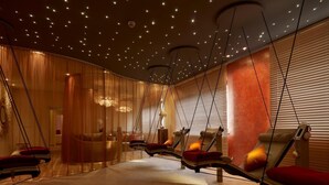 Un cuarto de spa con varias sillas de masaje, piso de madera e iluminación en el techo que simula estrellas.