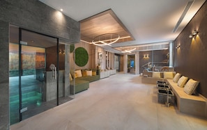 A modern lobby with a glass partition, a reception desk, and a seating area with a decorative wall. - Land  & Golf Hotel Stromberg (Stromberg)