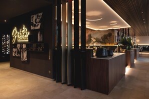 A modern interior with a reception desk, a wall-mounted sign reading 'Garden Restaurant,' and a large abstract painting. - Land  & Golf Hotel Stromberg (Stromberg)
