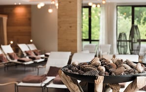 A modern interior with a seating area, a central table with pine cones, and large windows. - Land  & Golf Hotel Stromberg (Stromberg)