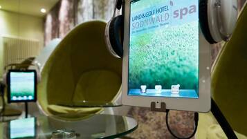 En digital skärm på en stol visar texten ”LAND&GOLF HOTEL SOONWALD spa” tillsammans med bilder som har ett välbefinnande-tema.