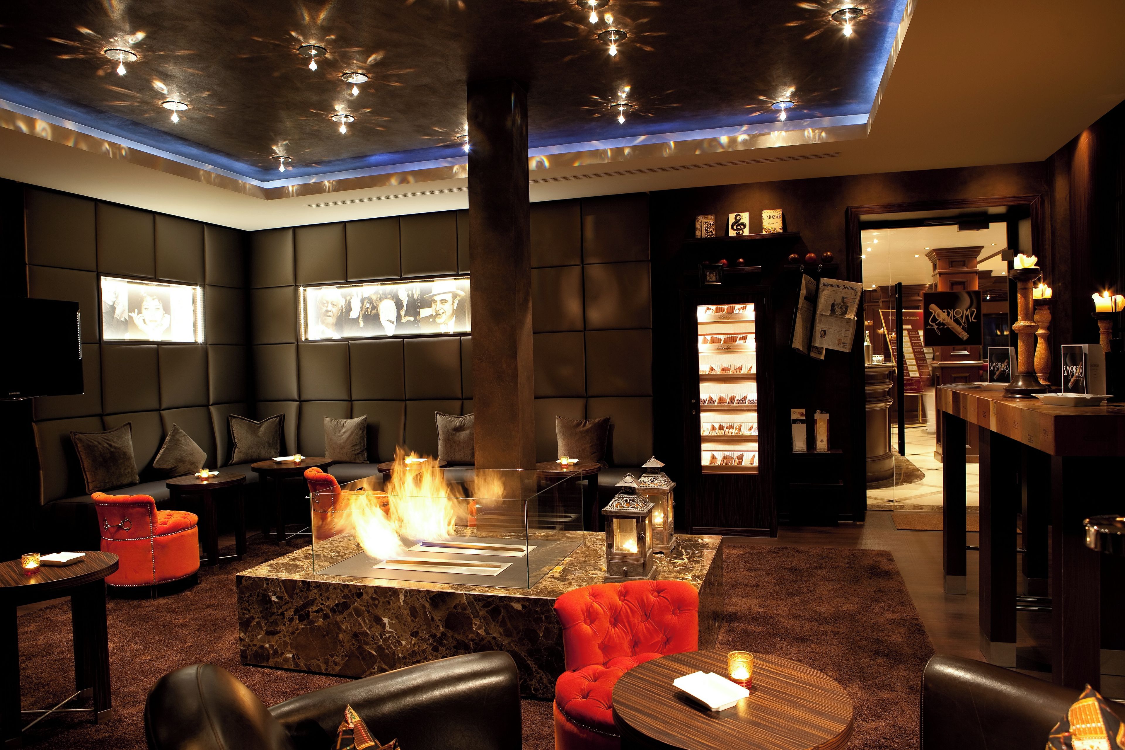 Ein stilvoller Lounge-Bereich mit einem zentralen Kamin, Ledersitzmöbeln und einer Bar mit Flaschenausstellung.