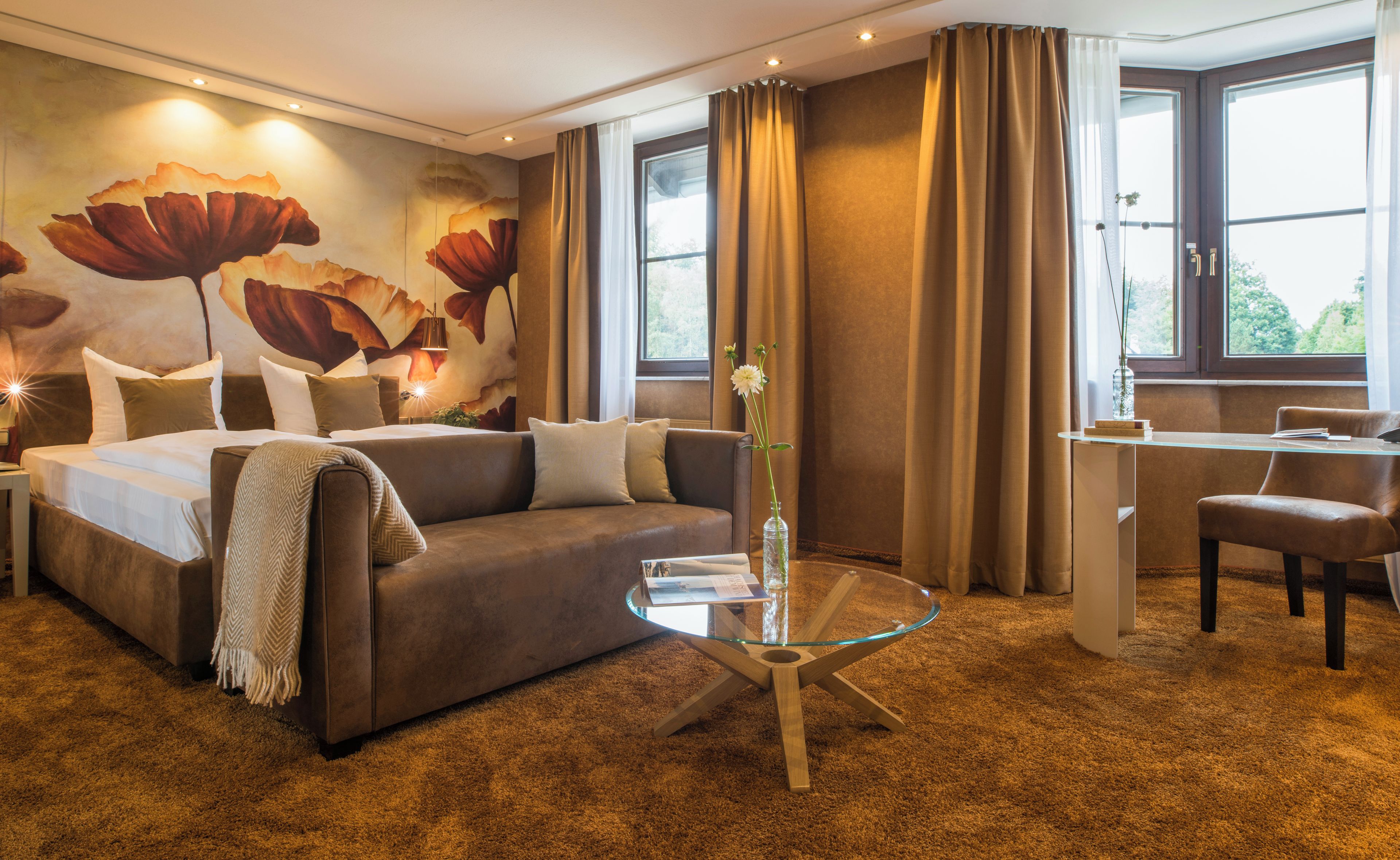 Una habitación de hotel con cama, una mesita de vidrio, un escritorio y una silla.