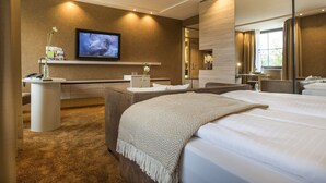 Habitación de hotel moderna con una cama grande, un escritorio con computadora, televisión y un espacio para el baño.
