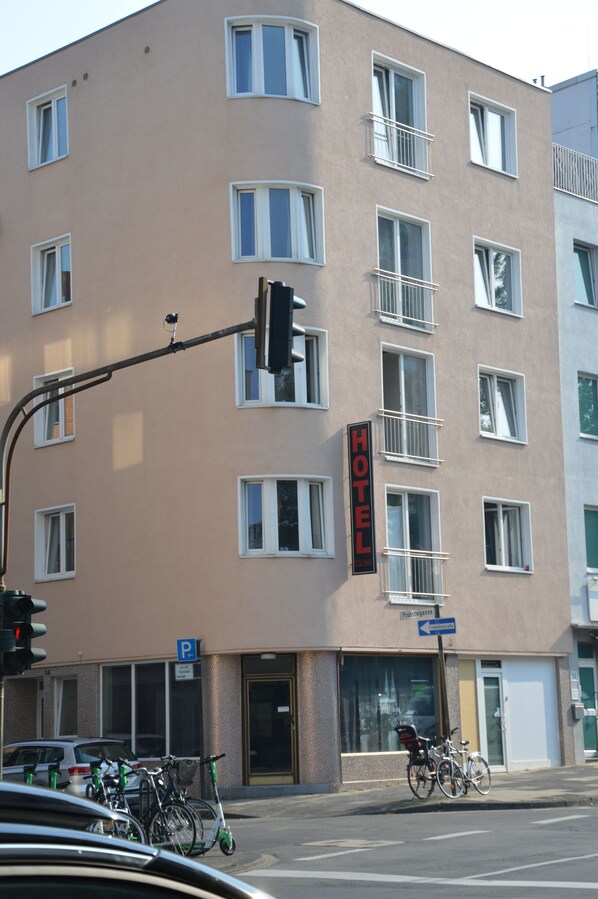 A multi-story hotel with a sign indicating it is a hotel. There are bicycles parked outside and a traffic light visible.