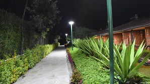 Un chemin bordé de verdure et un bâtiment doté d’un toit en pente.