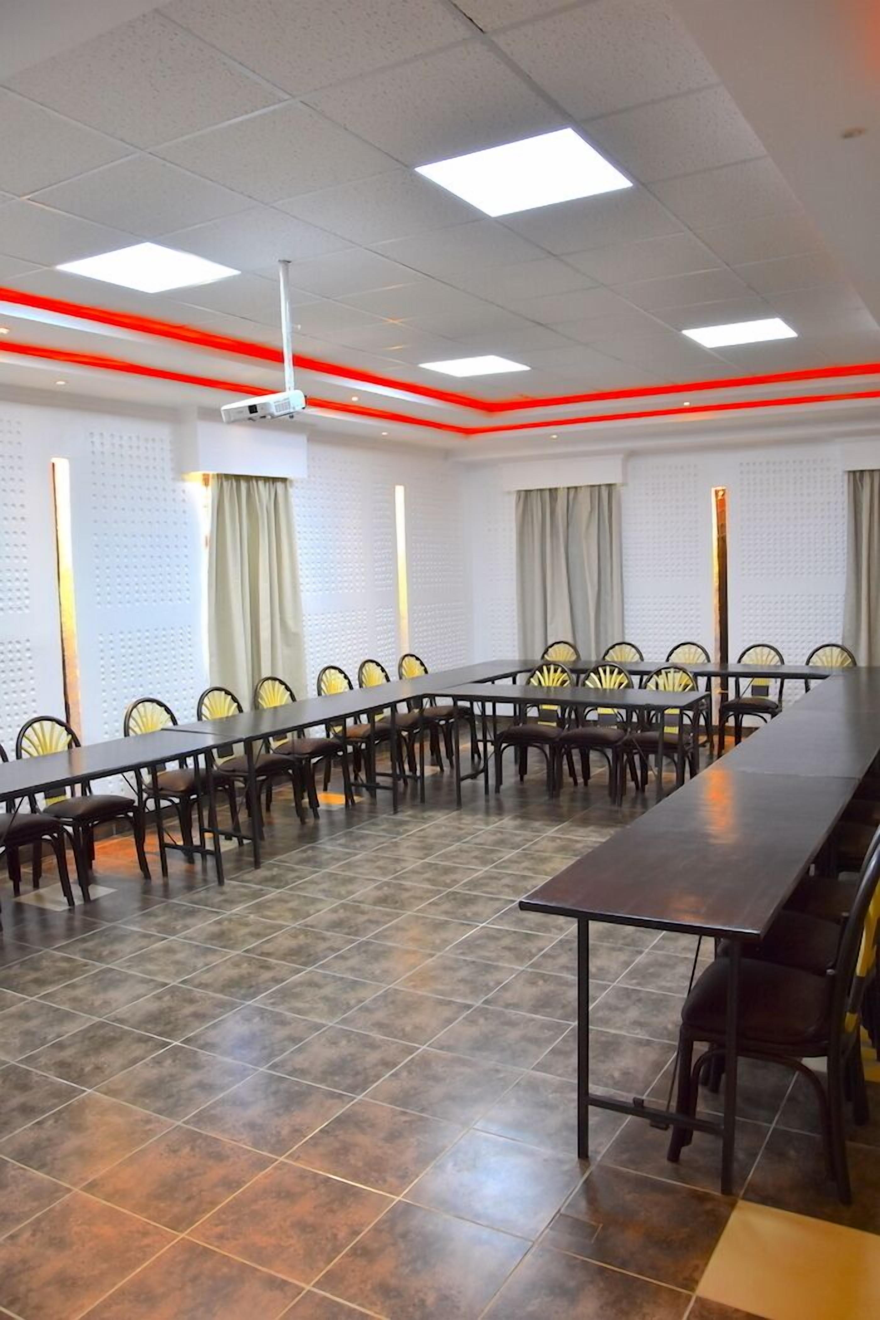 Een vergaderruimte met een lange tafel en stoelen, witte muren en rode accentverlichting.