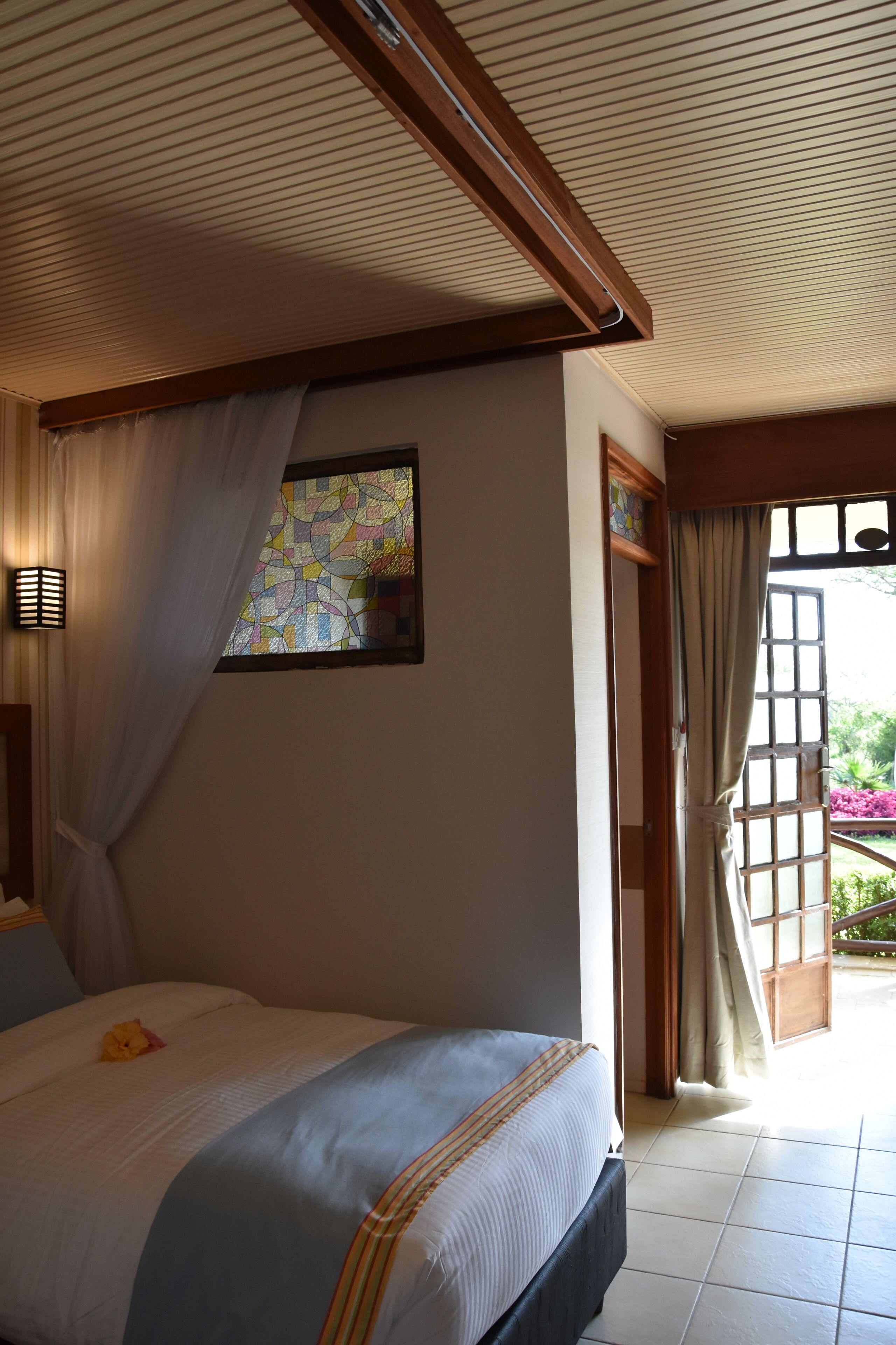 Une chambre à coucher avec un lit, une fenêtre ornée de vitraux et une vue sur l’extérieur.