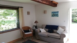 A room with a sofa, a chair, a lamp, and a painting on the wall. - Le Cottage de Cour la Ville (Le Mesnil-sur-Blangy)