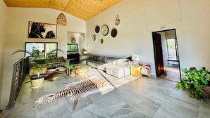 A spacious living area with a high ceiling, a sofa, a coffee table, and a zebra rug. - Little Forest Garden Retreat Guesthouse (Windhoek)