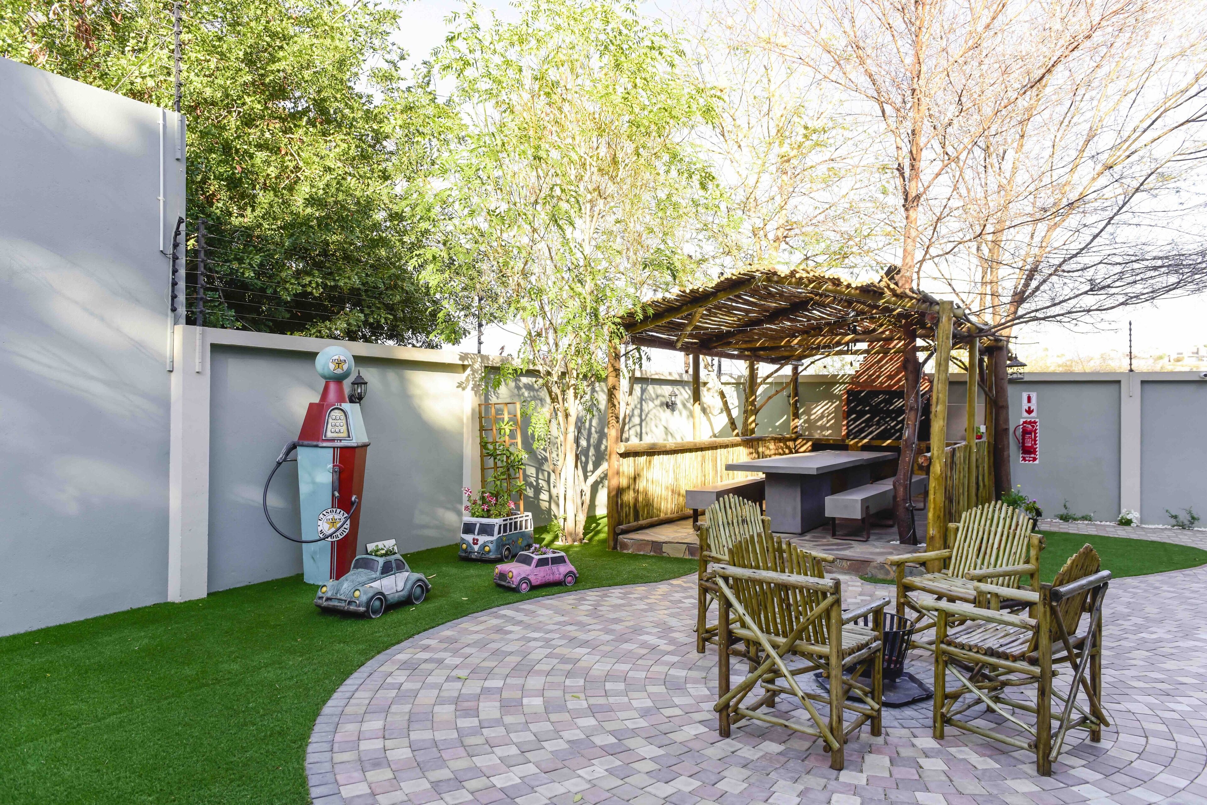 Un patio con una pérgola de madera, mobiliario exterior y césped artificial.
