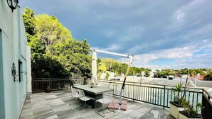 A rooftop terrace with a dining table and chairs, surrounded by a metal railing and potted plants. - Little Forest Garden Retreat Guesthouse (Windhoek)