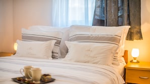 Een net opgemaakt bed met streepkussens en een dienblad met een mok en lekkernijen.