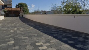 A paved driveway leading to a building with a tiled roof, a white wall, and a tree. - Beautiful one bedroom apartment in Porec (Vrvari)