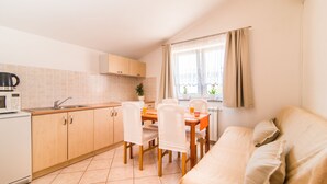 A compact kitchen with a dining area, a sofa, and a window with curtains. - Beautiful one bedroom apartment in Porec (Vrvari)