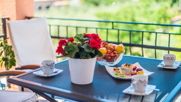 A balcony with a table set for breakfast, including a potted plant, fruits, pastries, and cups. - Beautiful one bedroom apartment in Porec (Vrvari)