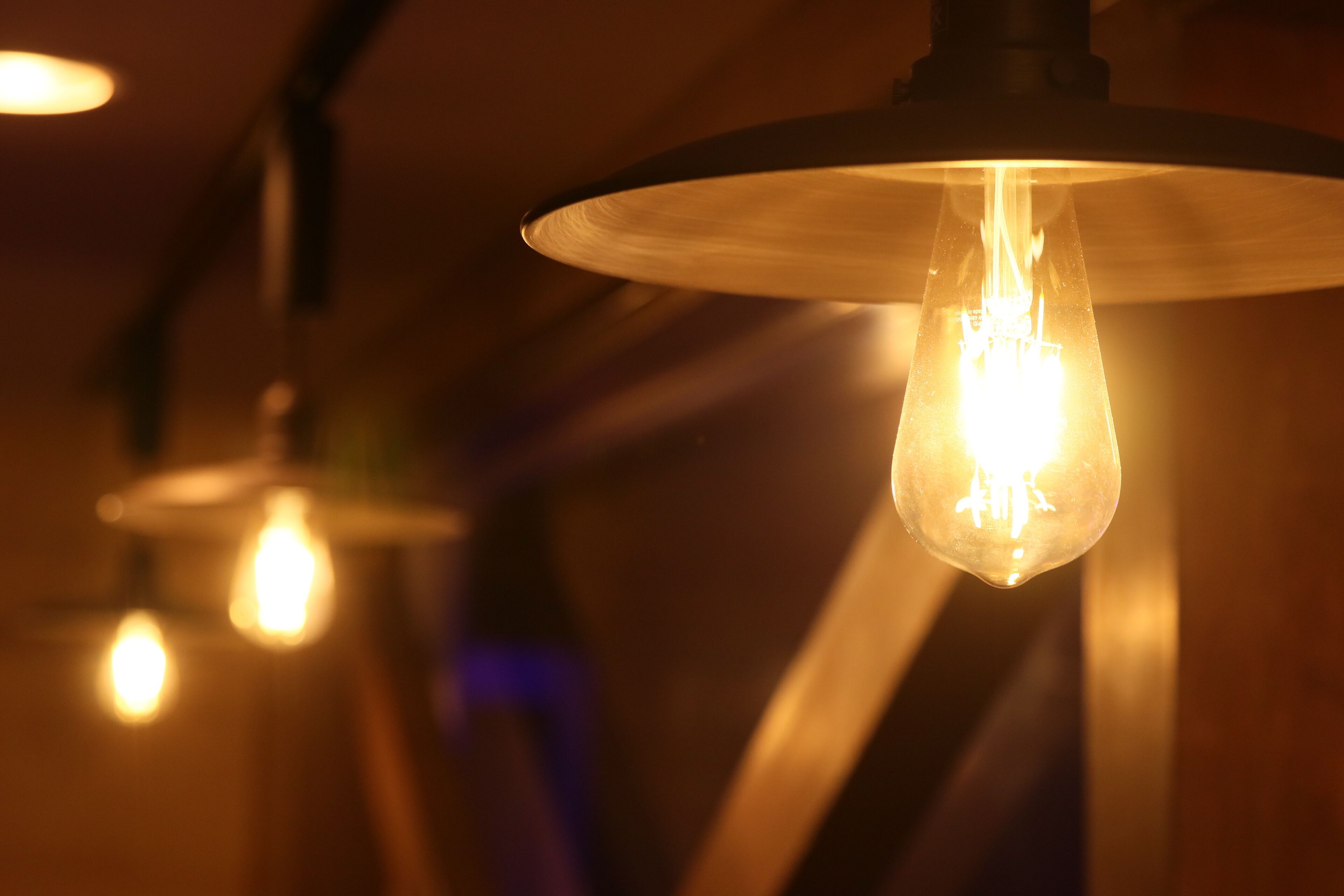 A close-up of a hanging light bulb with a visible filament.