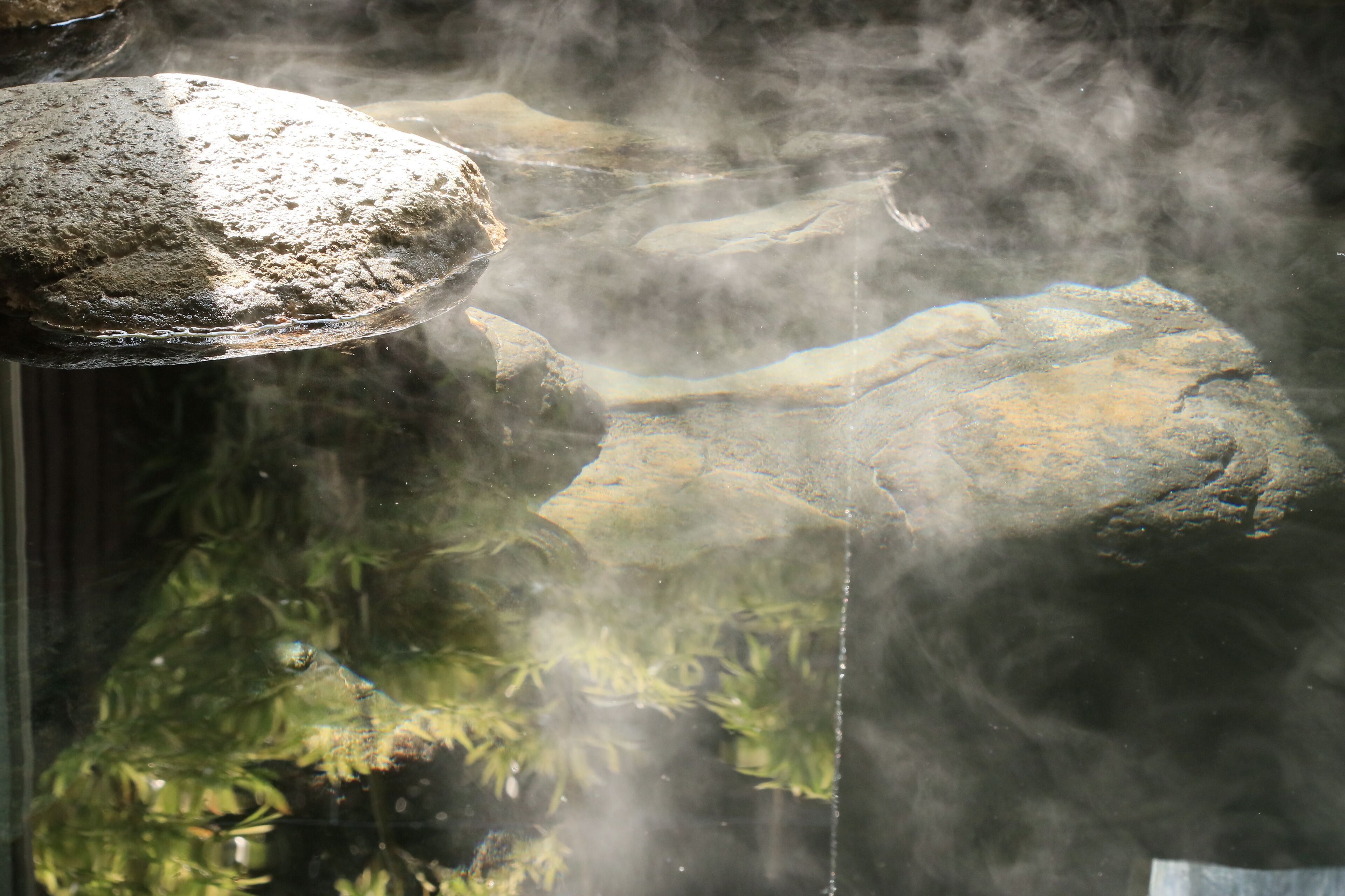 A rock formation with water flowing over it, creating a misty effect.