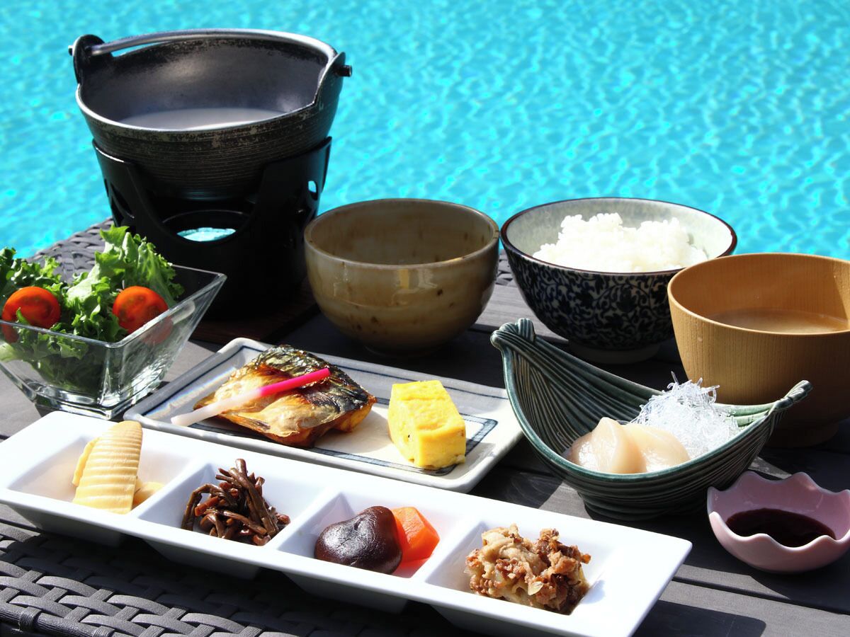 A table with various dishes and bowls, likely a meal setup by a poolside.