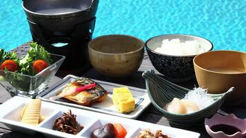 A table with various dishes and bowls, likely a meal setup by a poolside.