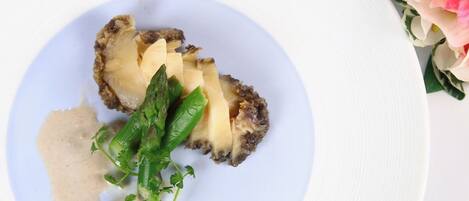 A plate with a food item, possibly a mushroom, garnished with green herbs and a creamy sauce.